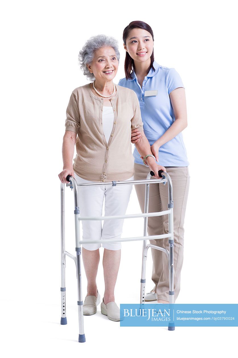 Chinese female nursing assistant helping senior woman with walking frame