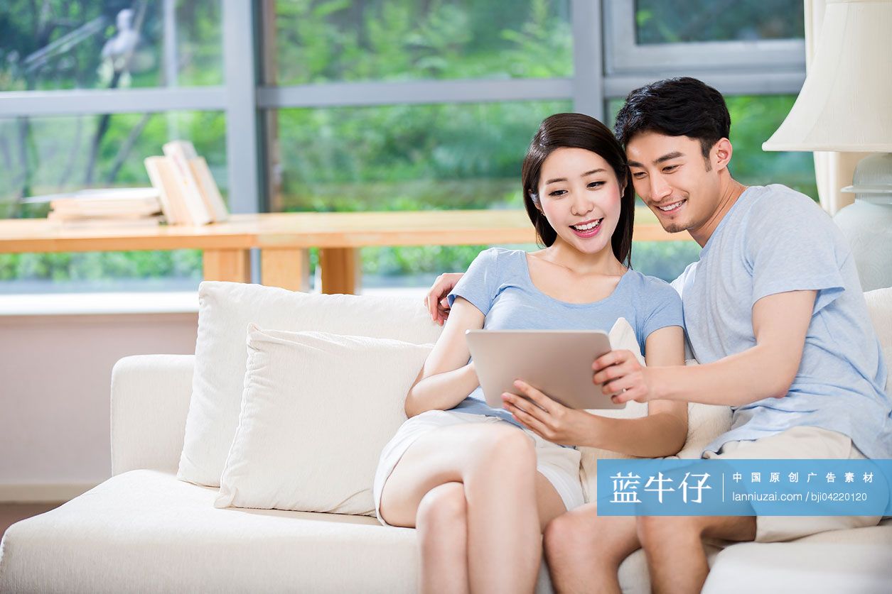 年轻夫妇在沙发上使用平板电脑