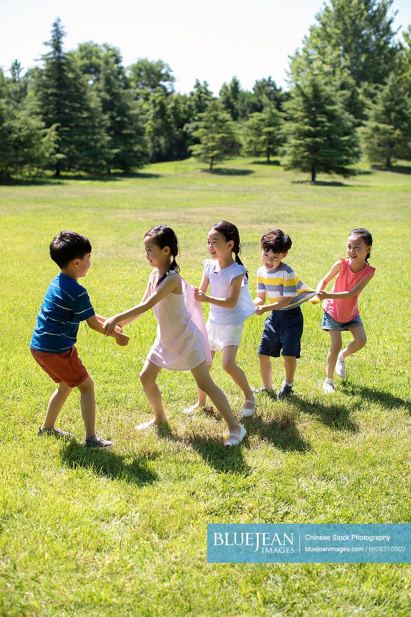 Happy Chinese children playing games on meadow
