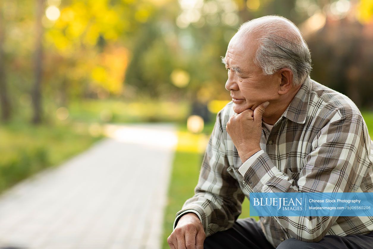 Lonely senior Chinese man thinking in the park