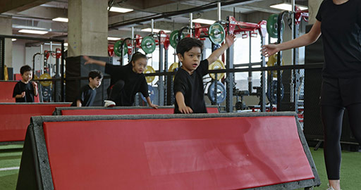 Active Chinese children having exercise class with their coach in gym,4K