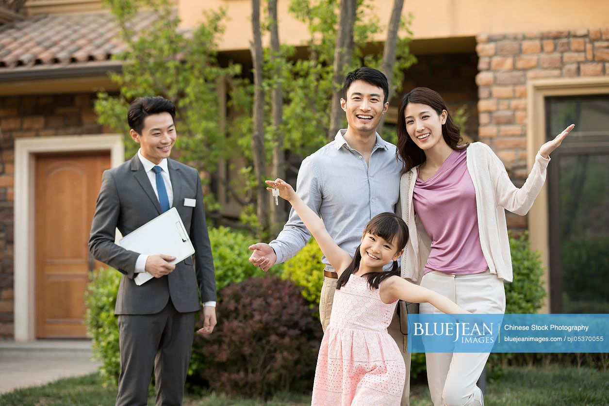 Happy young Chinese family holding keys to new house