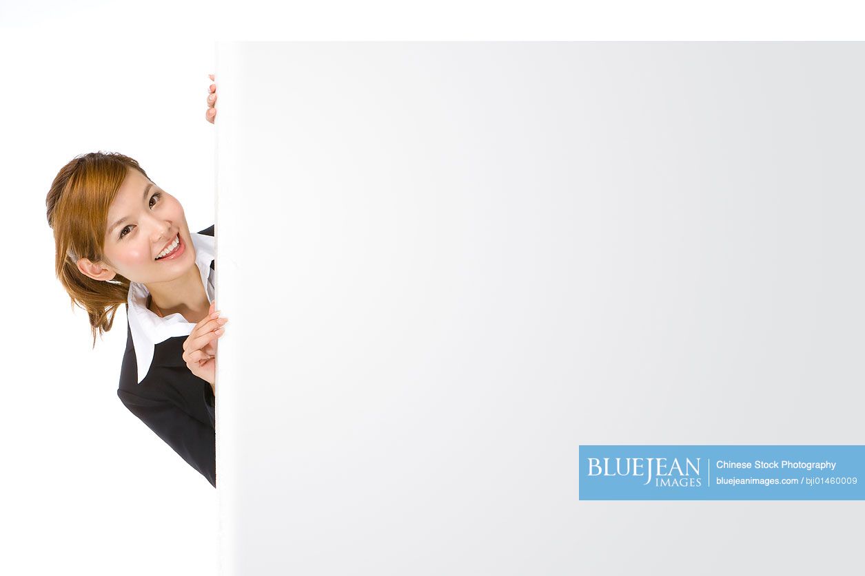 Chinese businesswoman peeking from behind blank placard