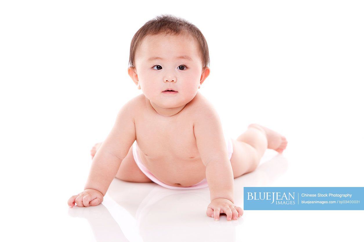 Studio shot of cute Chinese baby lying on floor