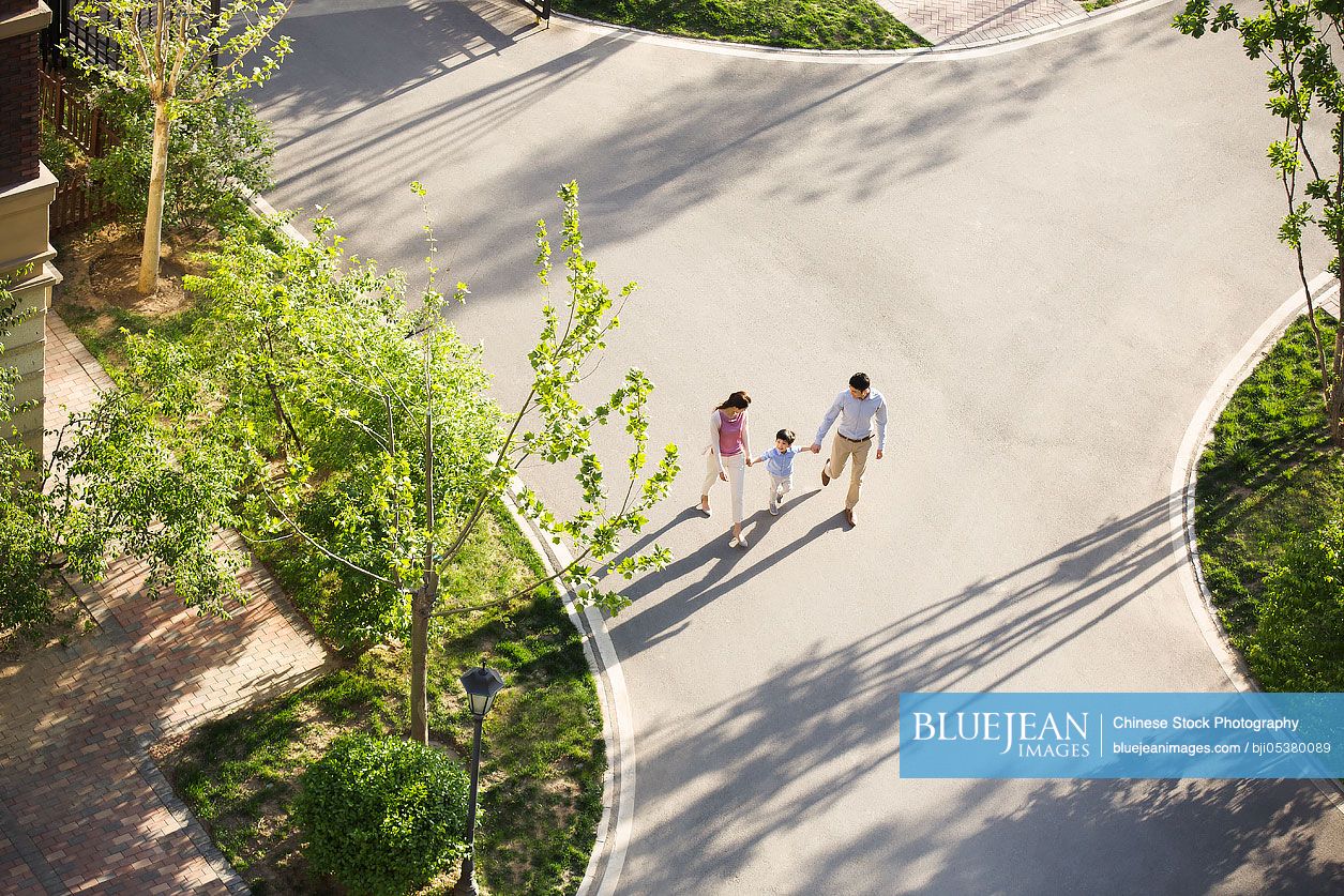 Happy young Chinese family holding hands walking