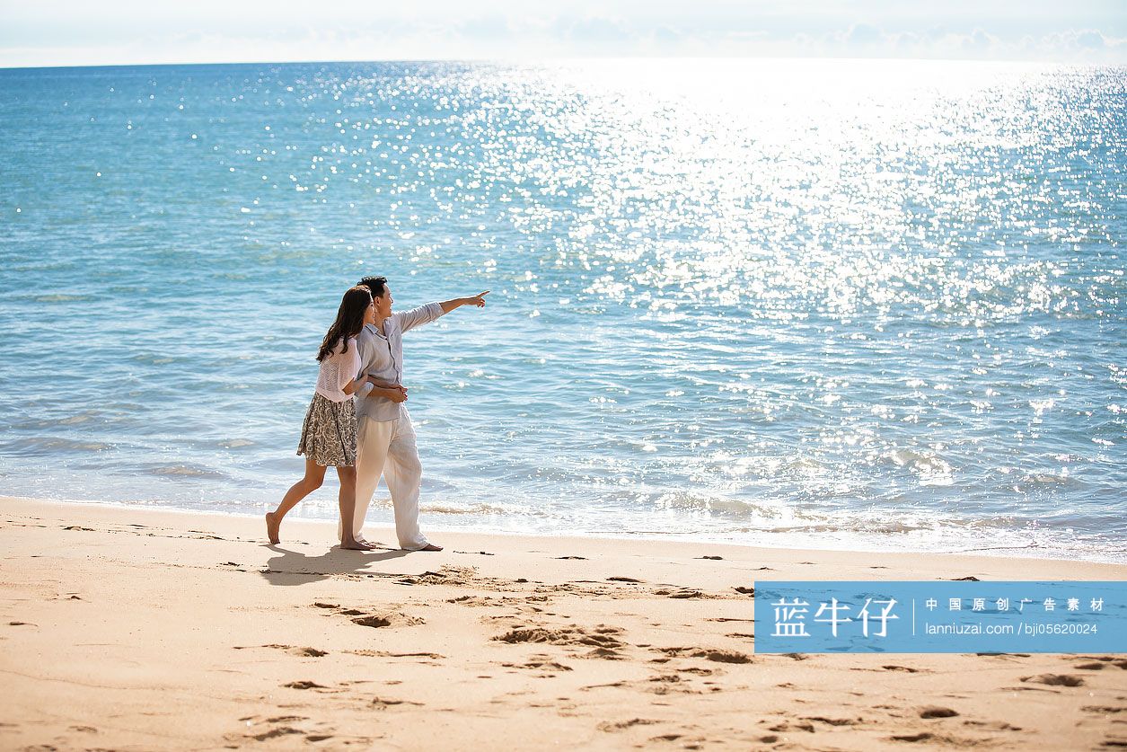 快乐的年轻夫妇在沙滩散步