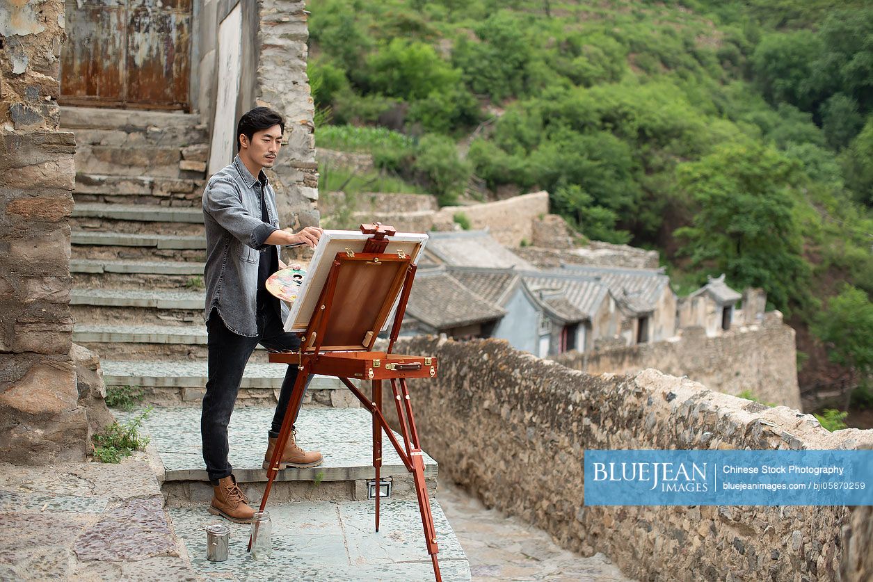 Young Chinese artist painting outdoors
