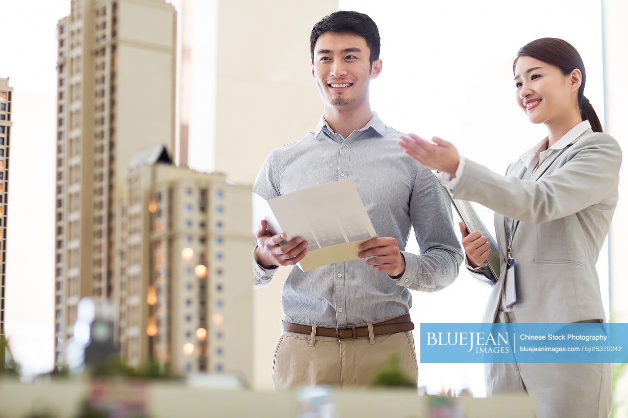 Chinese realtor showing architectural model to young manHighres stock
