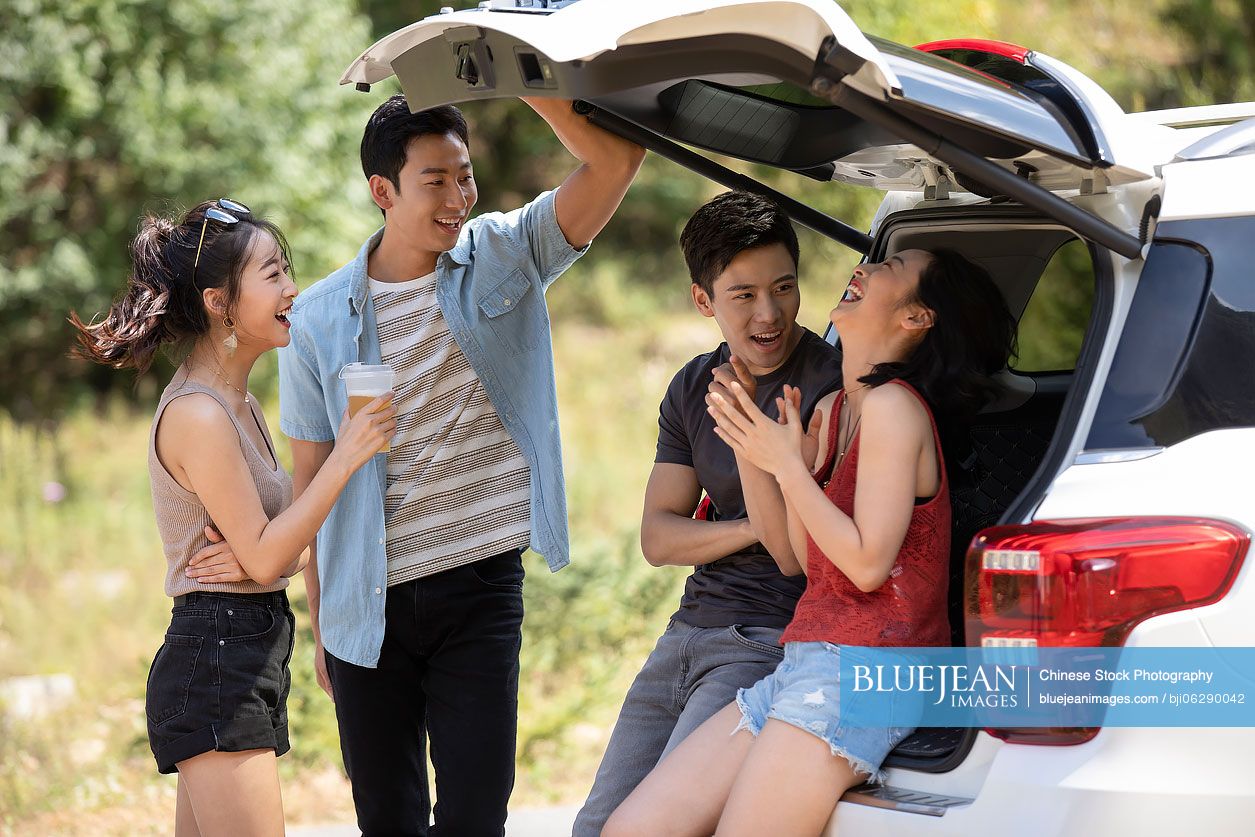 Happy young Chinese friends enjoying road trip