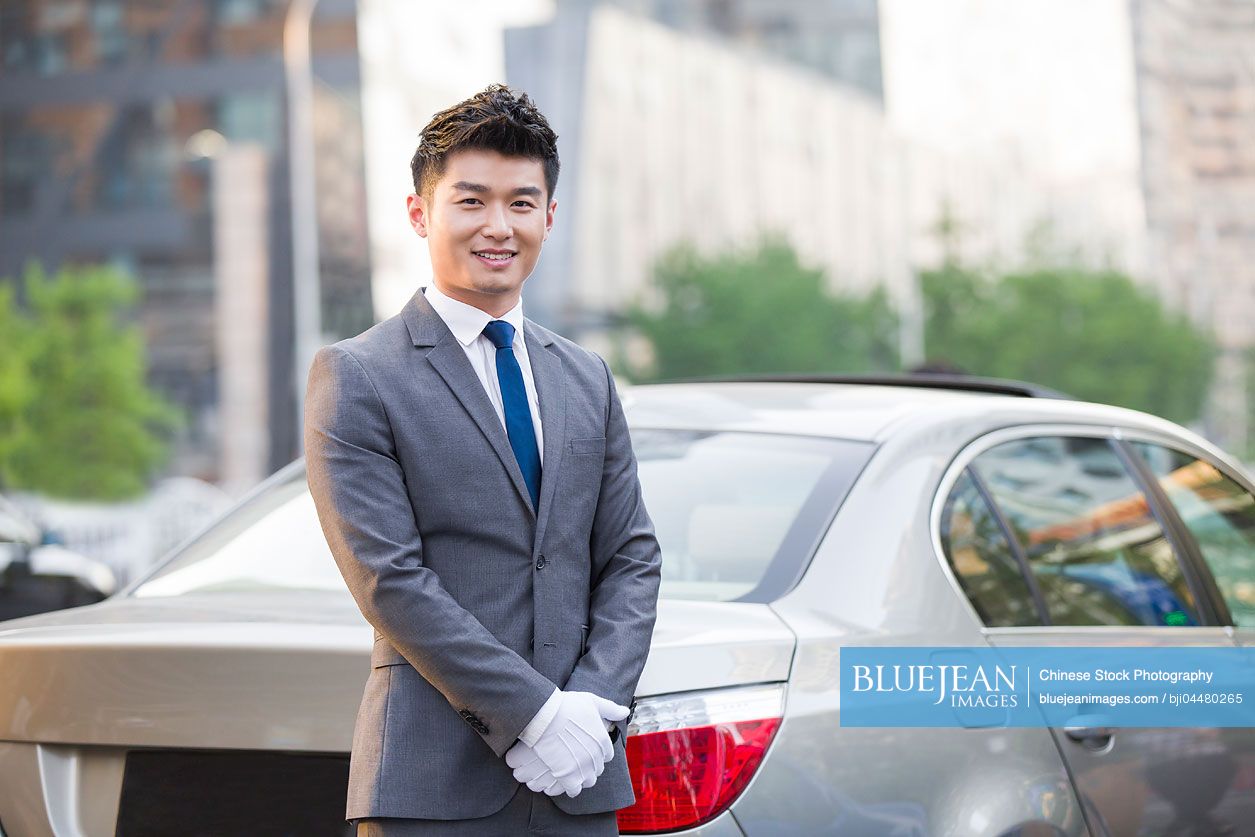 Portrait of Chinese chauffeur standing next to the car