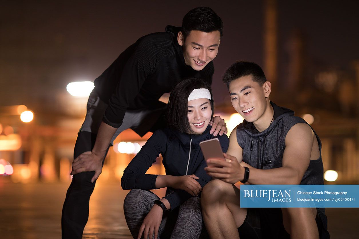 Young Chinese friends using smart phone