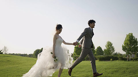 Happy bride and groom running on grass