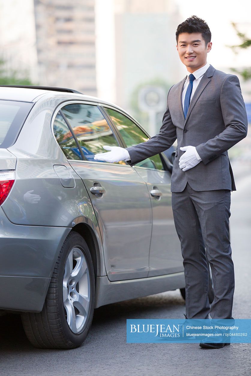 Portrait of Chinese chauffeur standing next to the car