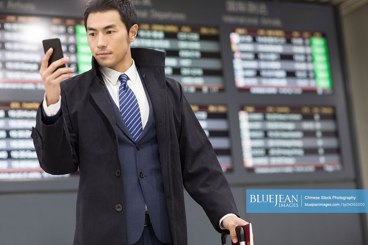 Young Chinese businessman using smart phone in airport