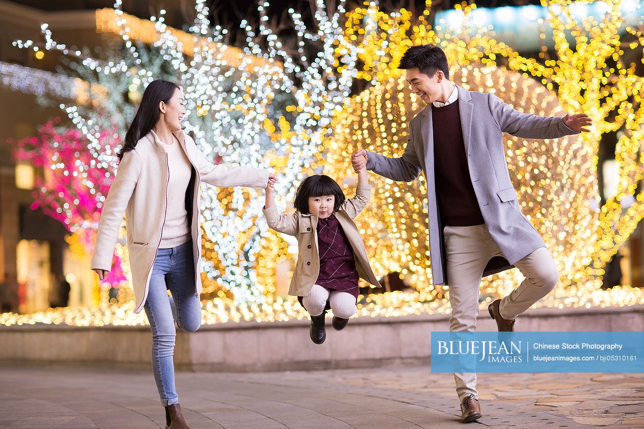 Cheerful young Chinese family playing outdoors