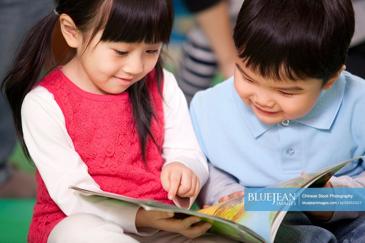 Cute little Chinese girl and little boy reading books