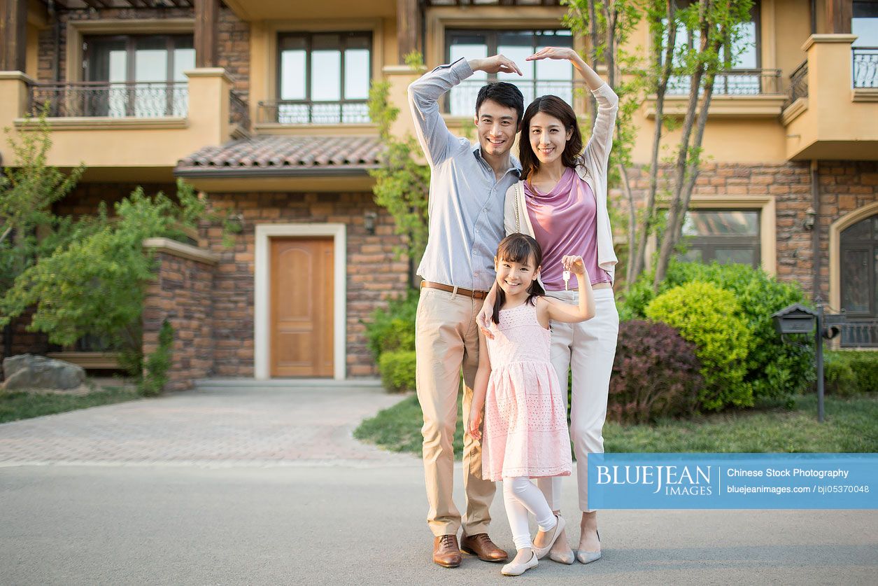 Happy young Chinese family holding keys to new house