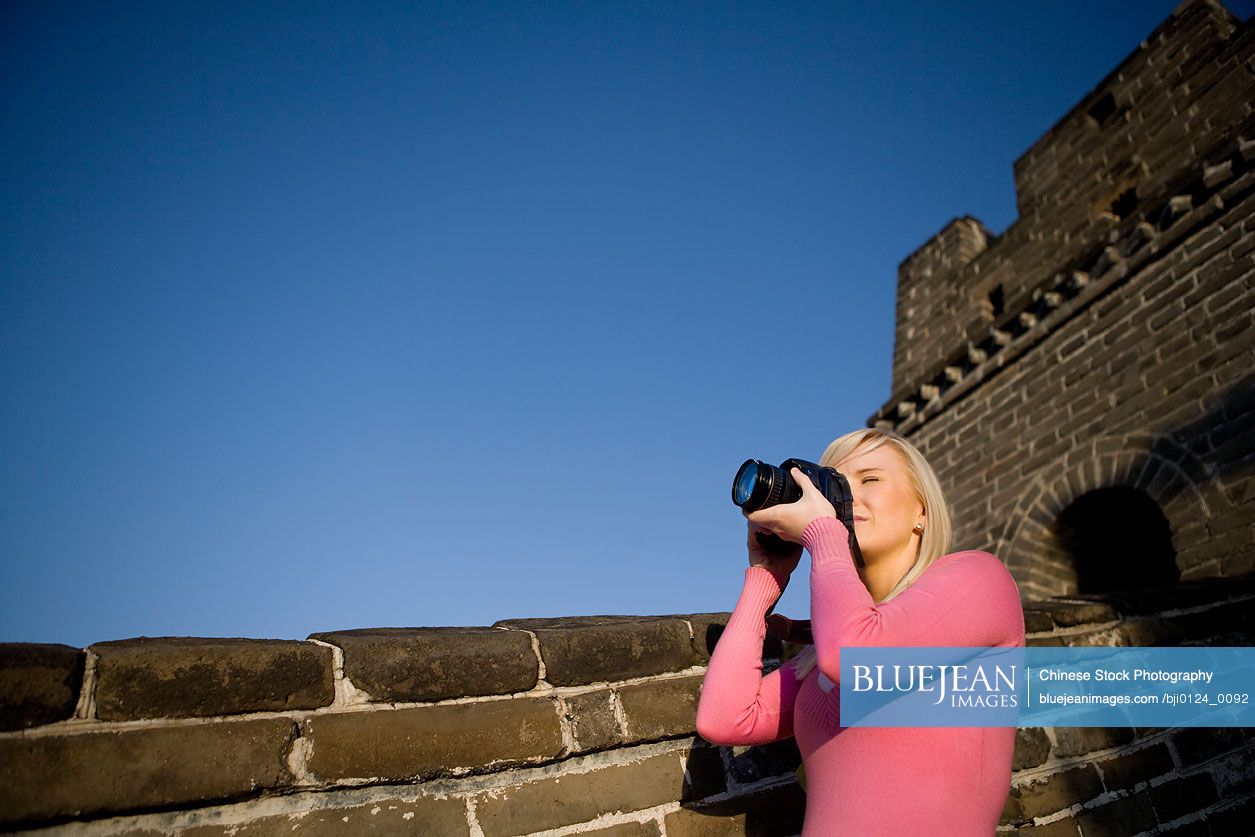 Young woman taking a photo at the Great Wall of China