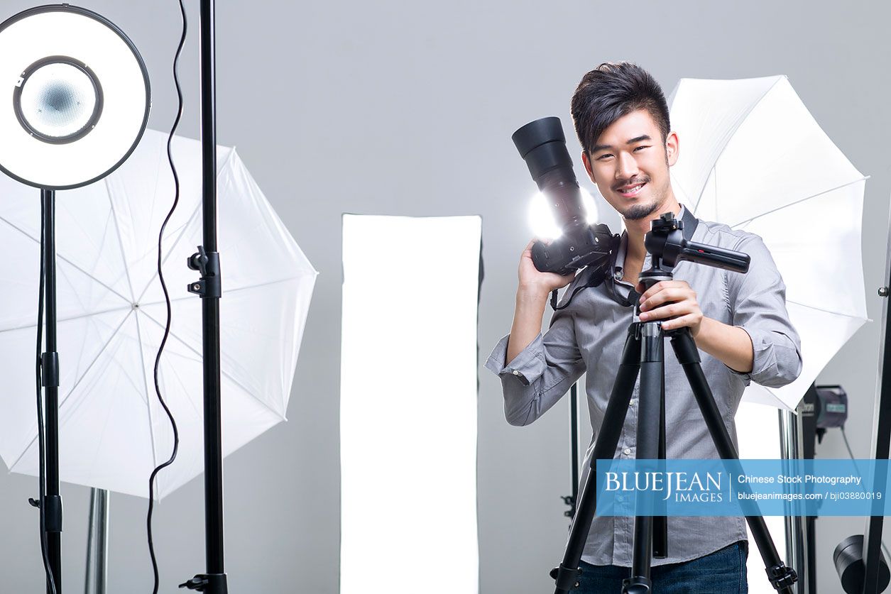 Chinese photographer standing in studio with camera