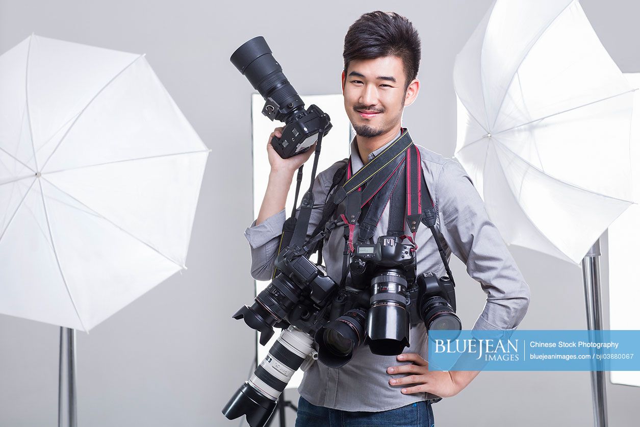 Portrait of Chinese photographer with many cameras hanging on his neck