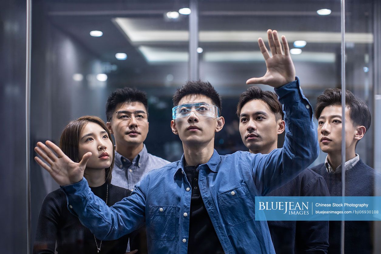 Confident Chinese designers checking futuristic glasses