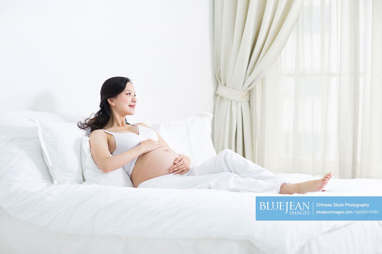 Pregnant Chinese woman resting in bed