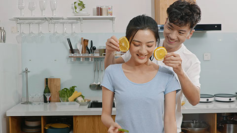 Happy young Chinese couple eating fruit in kitchen,4K