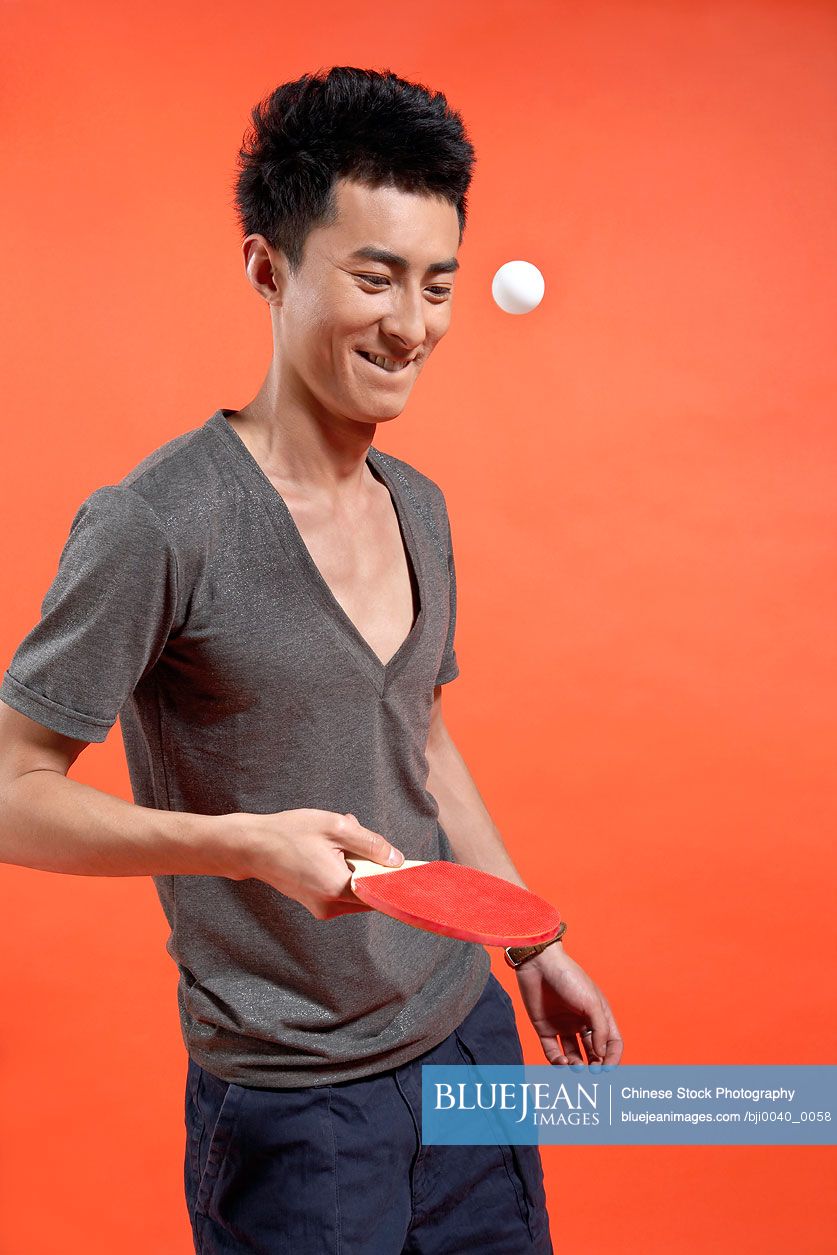 Young Chinese man hitting ping-pong ball