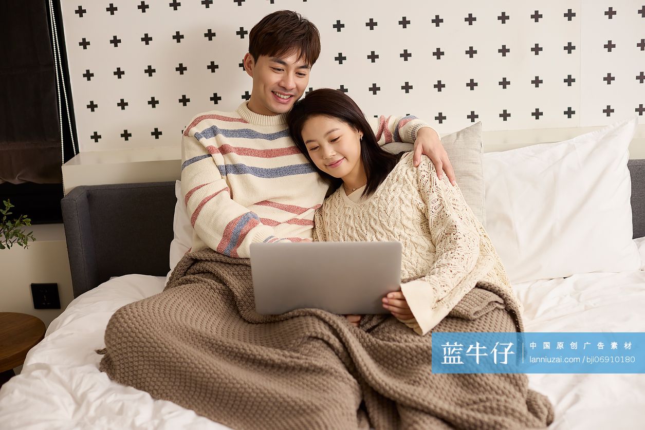 年轻情侣躺床上玩电脑