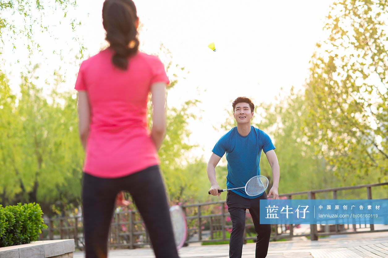 快乐的年轻情侣在公园打羽毛球