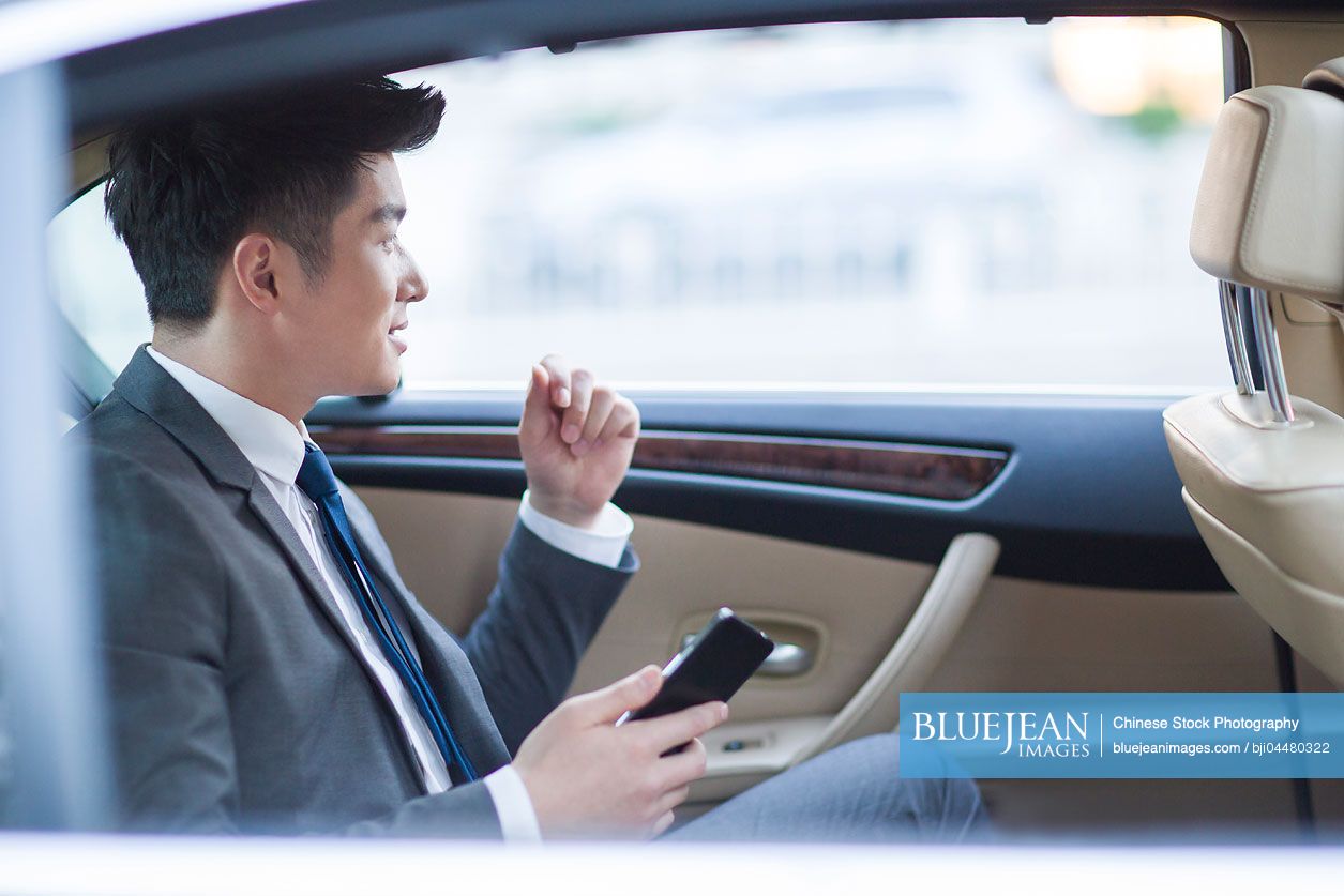 Chinese businessman sitting in car back seat