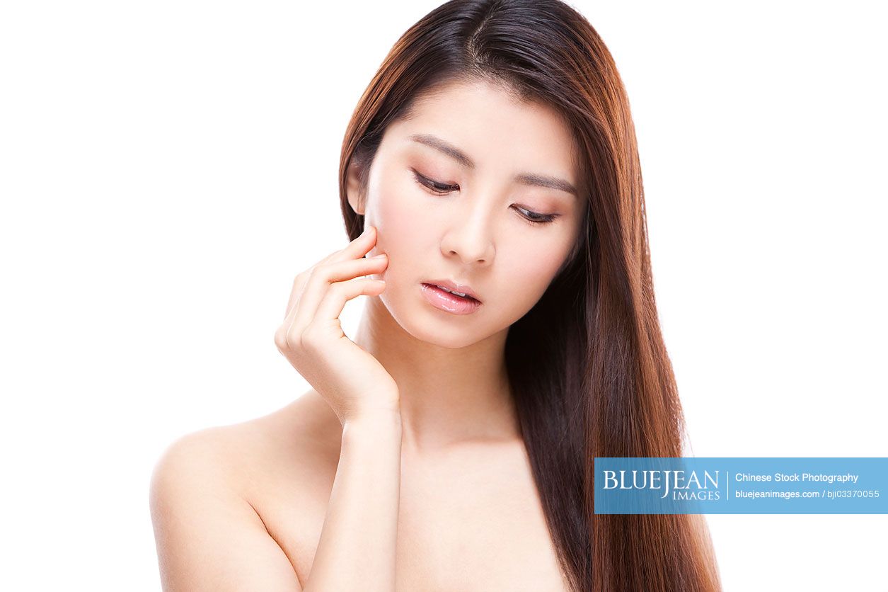 Young beautiful Chinese woman touching her face