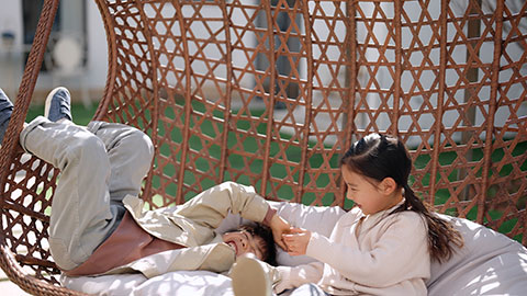 Happy little Chinese children relaxing on hanging-chair,4K