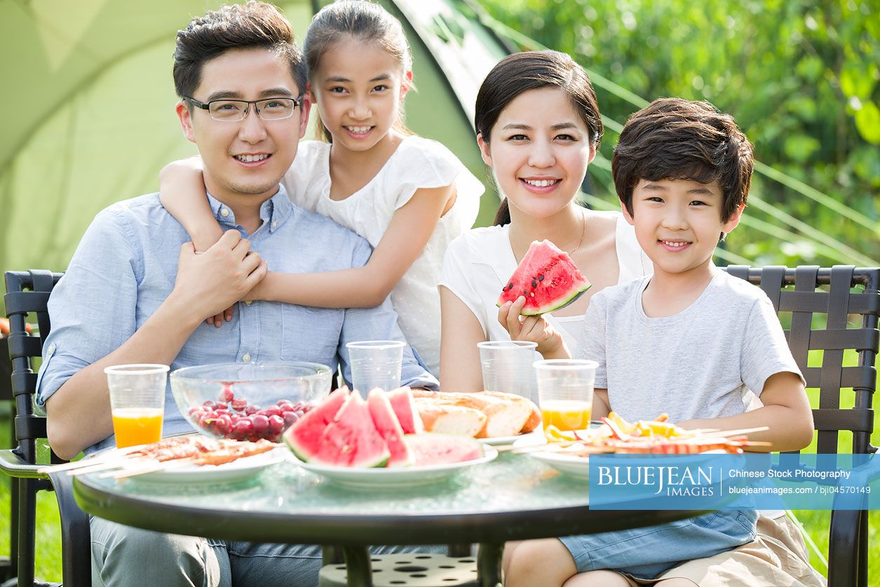 Young Chinese family picnicking outdoors