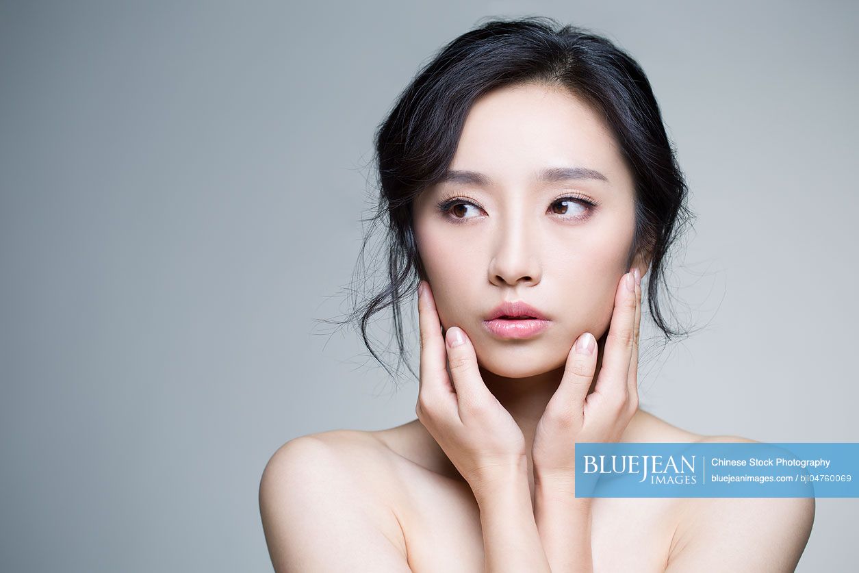 Young beautiful Chinese woman touching her face