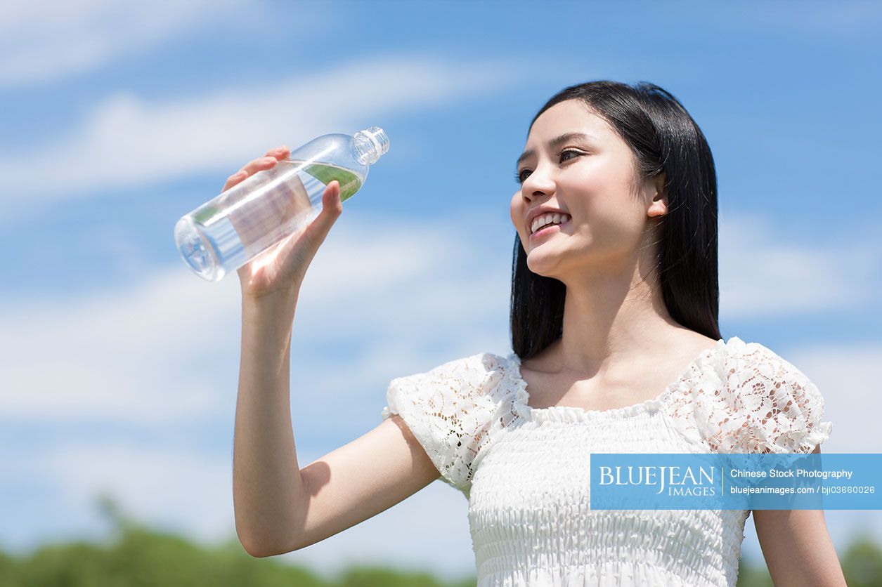 Young Chinese woman drinking water outdoors