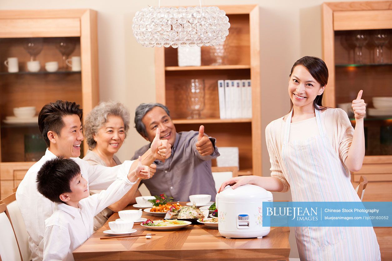 happy-chinese-family-showing-thumbs-up-at-meal-time-high-res-stock
