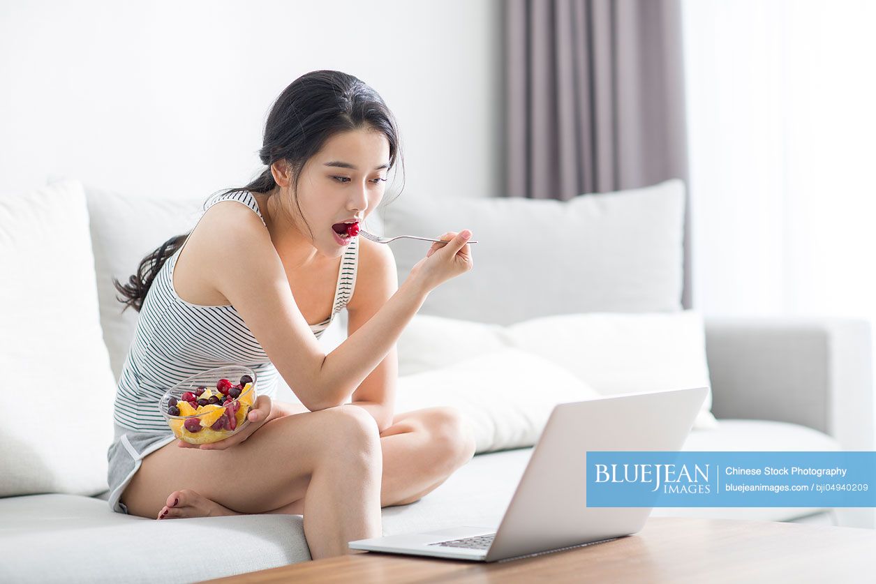 Young Chinese woman using laptop at home