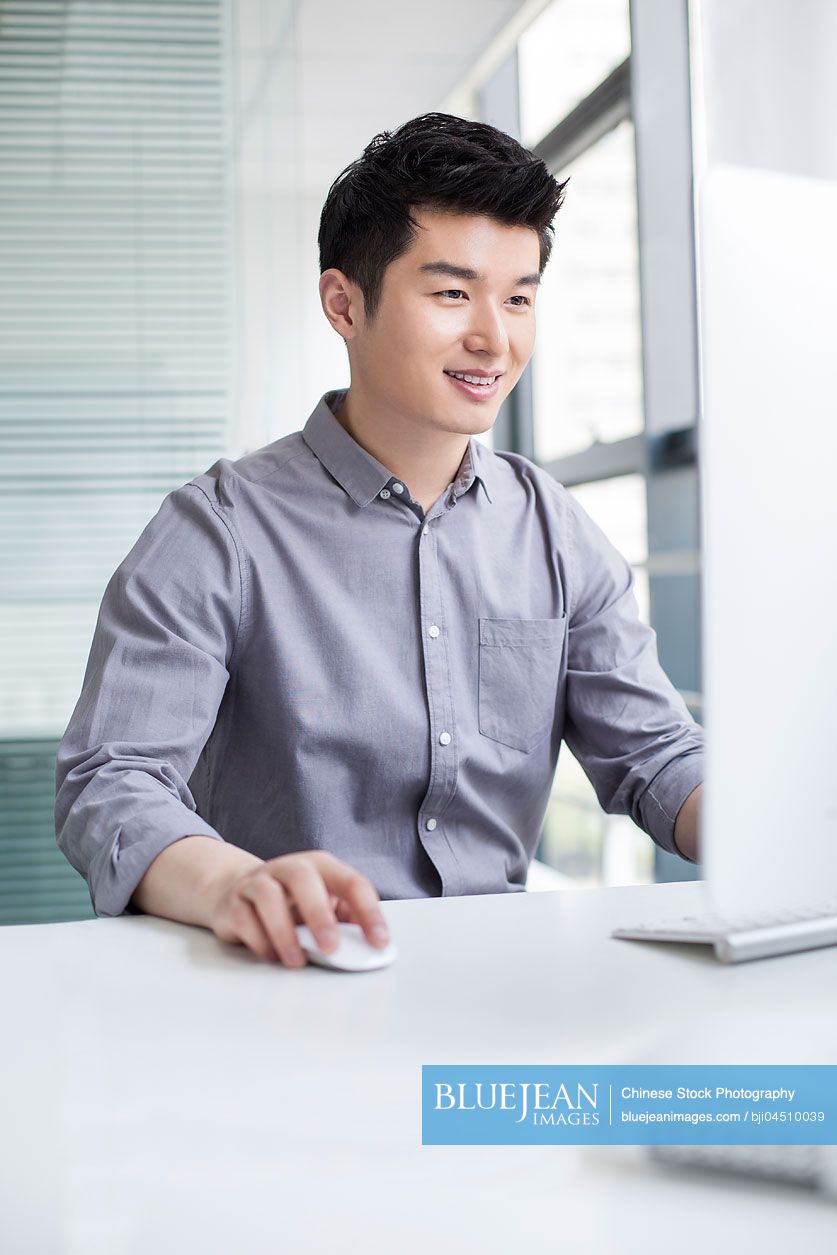 Young Chinese businessman using computer in office