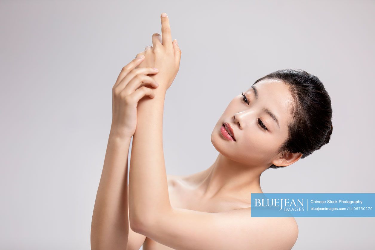 Beautiful young Chinese woman applying moisturizer