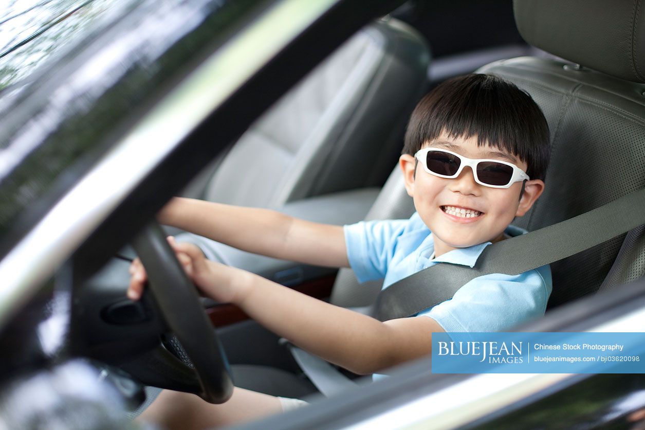 Excited Chinese boy pretending to drive car