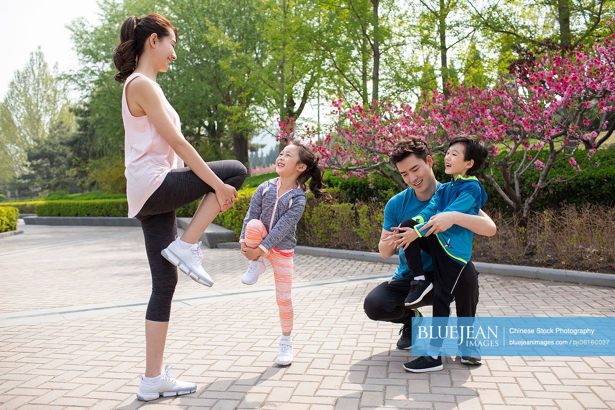Happy young Chinese family exercising in park