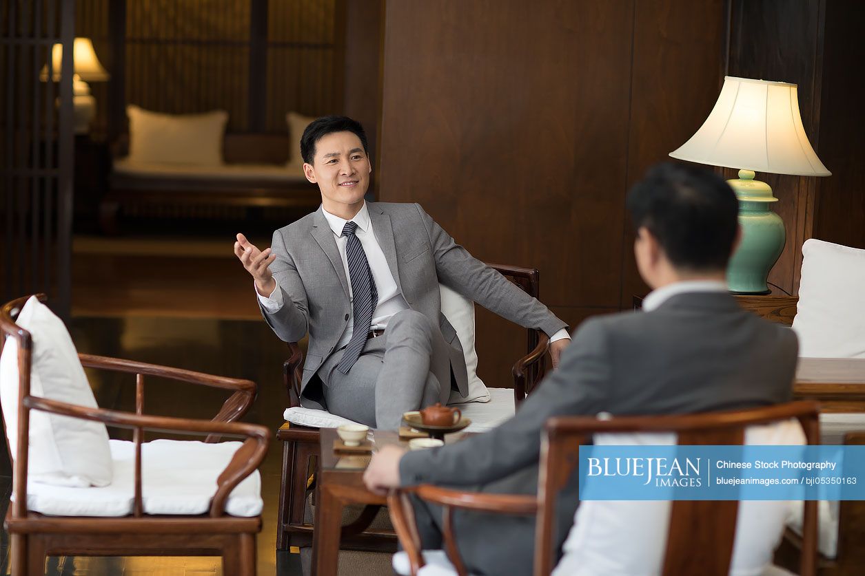 Cheerful Chinese businessmen talking in tea room