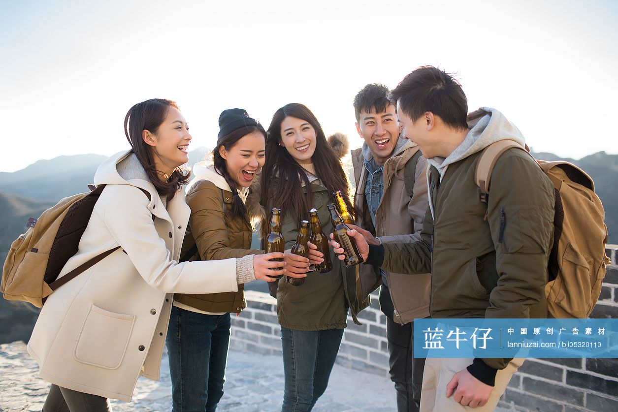 Happy young Chinese friends drinking beer on the Great Wall