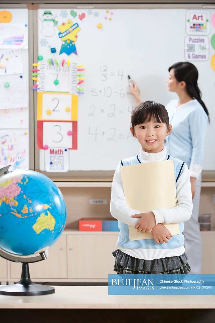 Young Chinese girl stands in the foreground as teacher teachers
