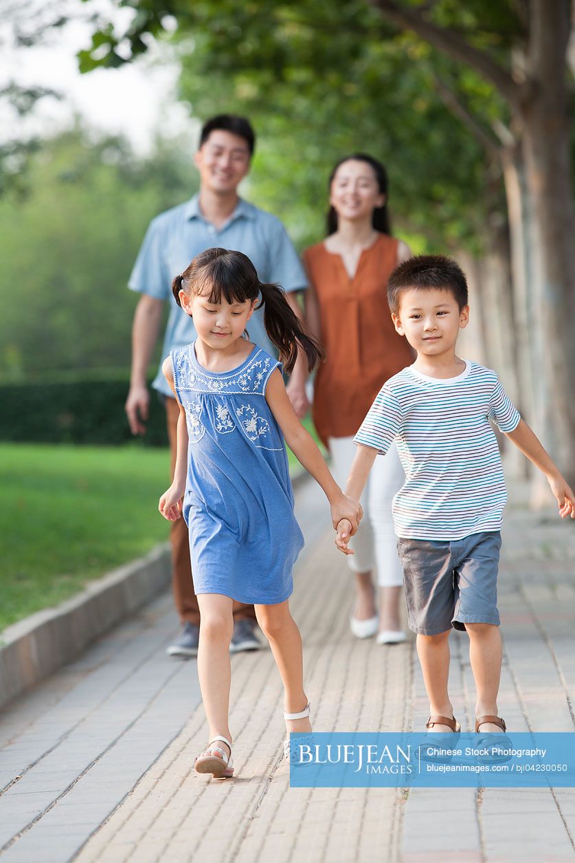 Happy Chinese brother and sister holding hands walking
