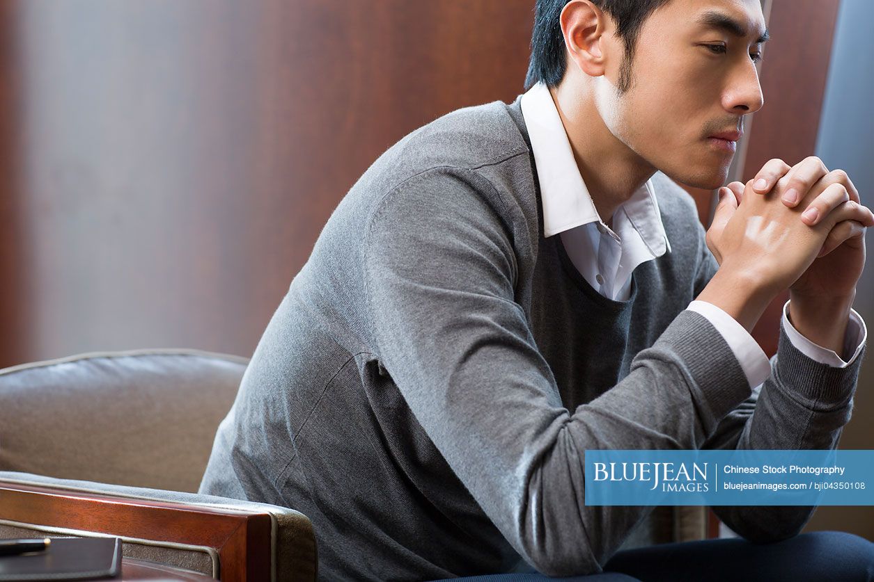 Young Chinese businessman thinking in hotel room