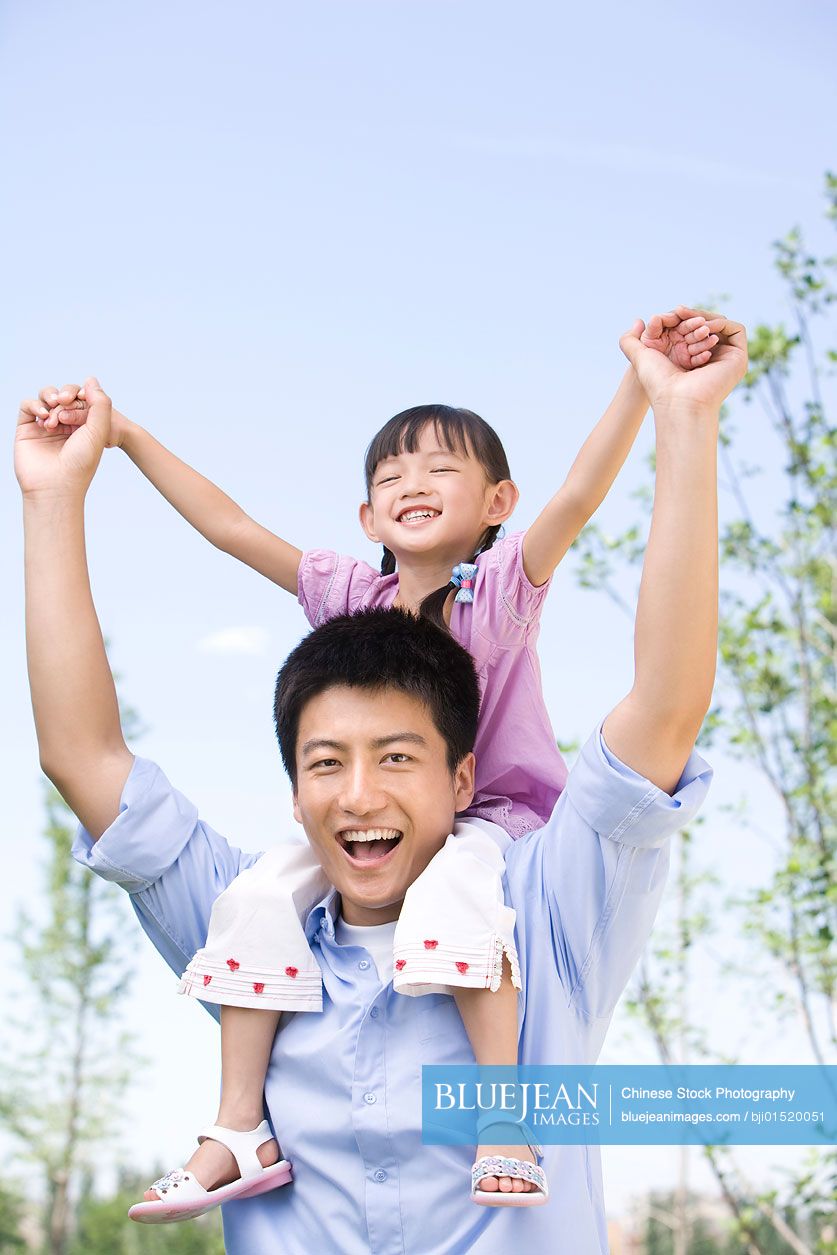 Chinese father carrying daughter on shoulder