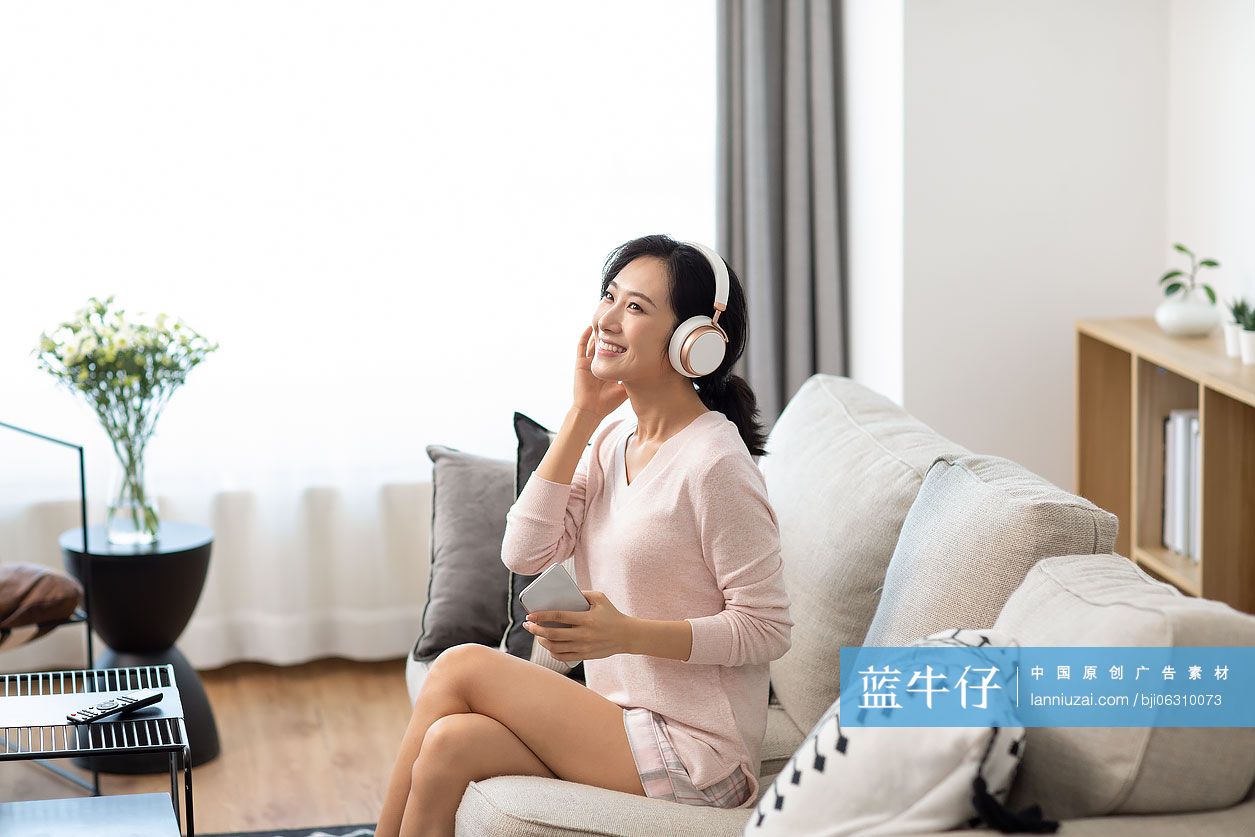 快乐年轻女士在家戴着耳机听音乐