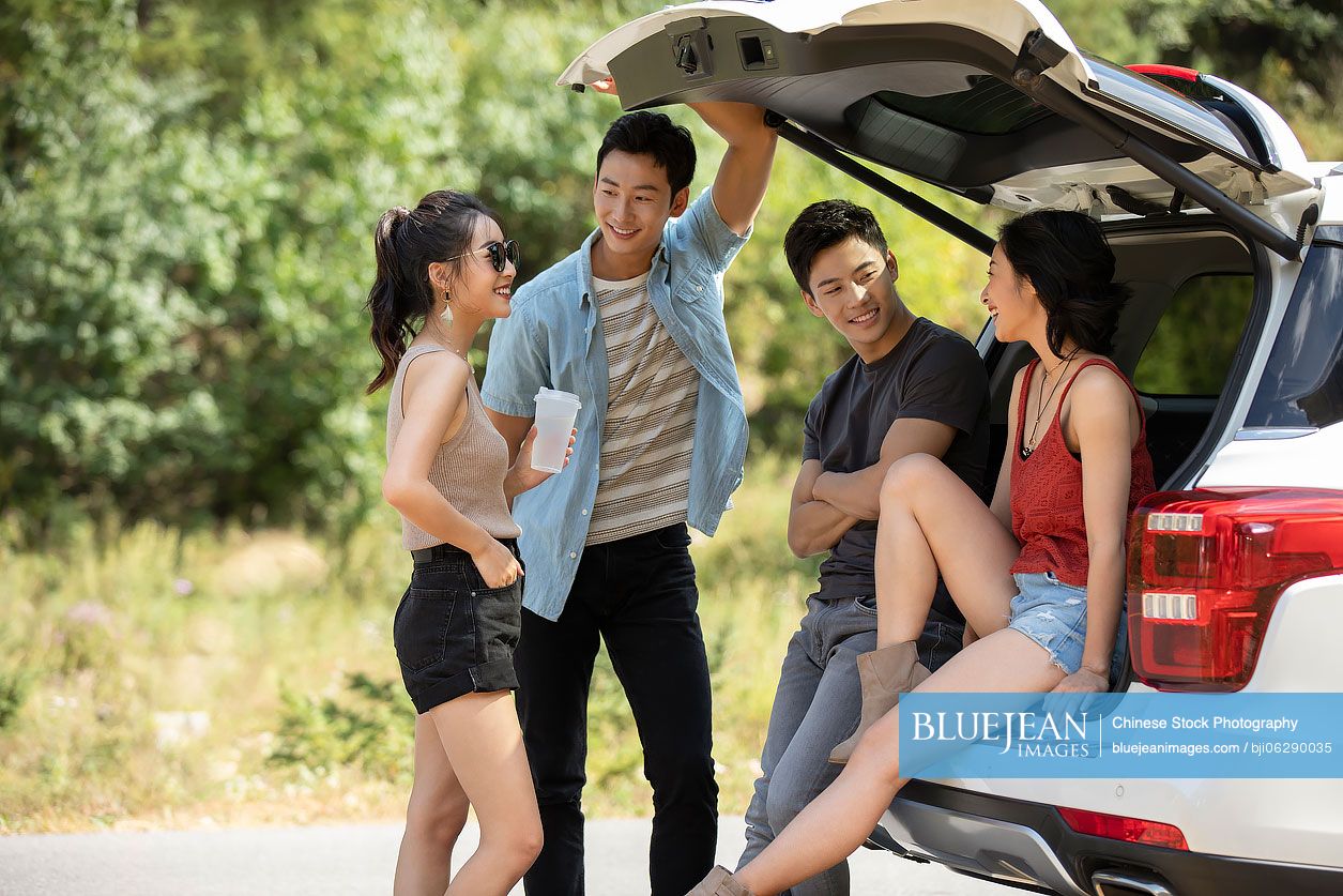 Happy young Chinese friends enjoying road trip